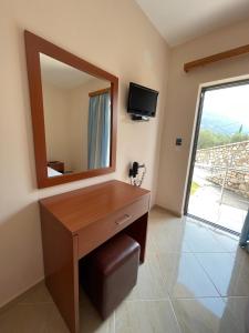 a bathroom with a vanity with a mirror and a television at Belvedere Hotel & Suites in Himare