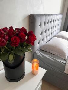 a vase of red roses on a table with a candle at Appartment. Quiet&Nice downtown in Oslo