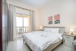 a white bedroom with a large bed and a balcony at Budget Friendly & Studio & Golf View in Ras al Khaimah