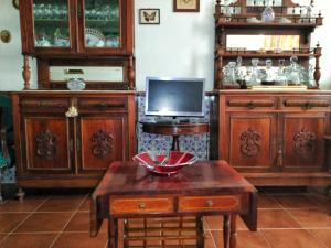 a living room with wooden furniture and a tv at Apartamento no coração da aldeia in Atouguia da Baleia