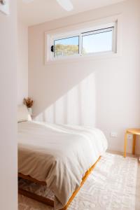 um quarto branco com uma cama e uma janela em Heights Guesthouse - Hideaway in Kiama Heights em Kiama