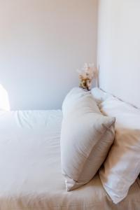 uma cama branca com almofadas brancas em Heights Guesthouse - Hideaway in Kiama Heights em Kiama
