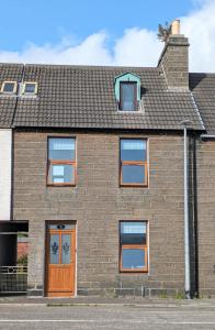 ウィックにある2 Bedroom Townhouse with Seaview on the NC500 Wickの褐色のドアと窓のあるレンガ造りの家