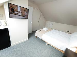 a bedroom with a bed with a flat screen tv on the wall at Osney Cypress Studio - Self Contained Studio Flat in Oxford