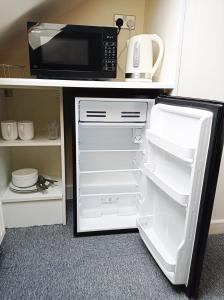 a kitchen with a microwave and a refrigerator with its door open at Osney Cypress Studio - Self Contained Studio Flat in Oxford