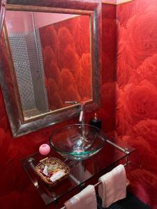 uma casa de banho vermelha com um lavatório de vidro e um espelho em El Secreto del Júcar em Casas de Ves
