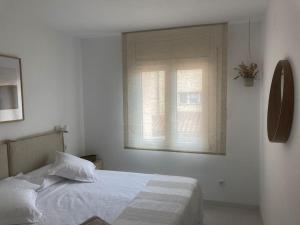 Habitación blanca con cama y ventana en Camí Ample, en L'Escala
