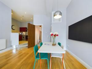 uma sala de jantar com uma mesa branca e cadeiras azuis em Fitzrovia Mansion Apartments in Belfast's Cathedral Quarter em Belfast