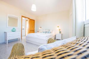 a white bedroom with a bed and two chairs at Aguamarina in Tarajalejo