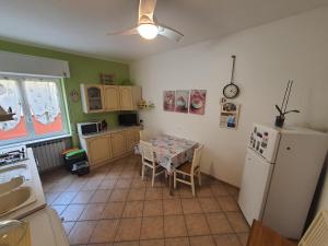 a kitchen with a table and a white refrigerator at Appartamento in centro a 30m dal mare in Spotorno