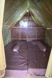 ein kleines Bett in einem Zelt mit zwei Kissen in der Unterkunft Bunga Jabe in Karimunjawa