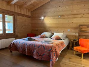 een slaapkamer met een bed in een houten hut bij Le Chalet du Crêt - 8 pers, tout confort avec Jacuzzi in Notre-Dame-de-Bellecombe
