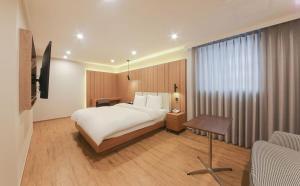 慶州市にあるH Avenue Hotelのベッドとテーブルが備わるホテルルームです。