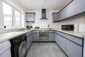 a kitchen with white cabinets and a washer and dryer at The worker’s nest in Cherry Tree