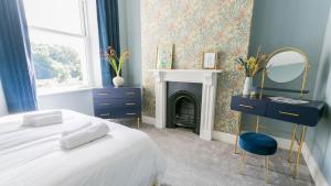 um quarto com uma cama, um espelho e uma lareira em Claremont em Llanfairfechan