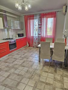 a kitchen with red cabinets and a table and chairs at Mitropolit Dosoftei Street Апартаменты in Chişinău