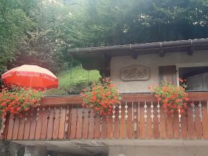 uma varanda com um guarda-chuva e flores sobre uma cerca em CASETTA INDIPENDENTE NEL VERDE PER 2/3 PERSONE em Breguzzo