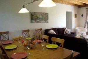 una sala de estar con una mesa de madera con platos verdes. en Grande maison avec parc de 6000m2, en Pompiey