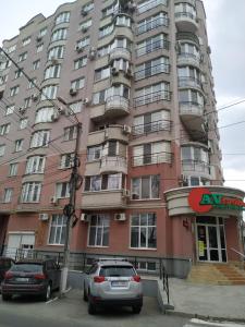 a tall pink building with cars parked in front of it at Mitropolit Dosoftei Street Апартаменты in Chişinău