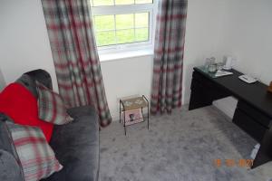 a living room with a couch and a desk and a window at The Old Coach House in Llangollen