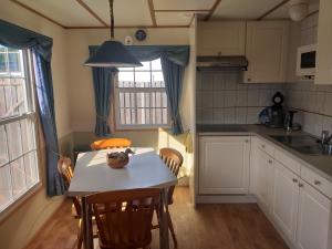 eine Küche mit einem Tisch und Stühlen sowie eine Küche mit einem Fenster in der Unterkunft tuinfluiter 50 in Oisterwijk