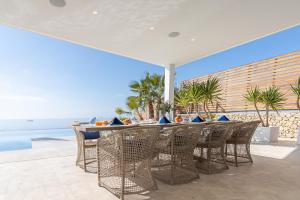 taras ze stołem i krzesłami i widokiem na ocean w obiekcie Blue Sky Mallorca Luxury Villa w mieście Andratx