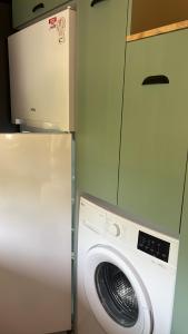 a washing machine in a kitchen next to a refrigerator at JULYA TİNY HOUSE in Cıralı