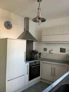 a kitchen with white cabinets and a stove at Le Sableau in Beauvoir-sur-Mer +3 photos