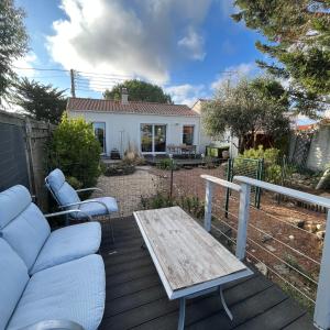 patio con tavolo e sedie in legno su una terrazza di Le Sableau a Beauvoir-sur-Mer