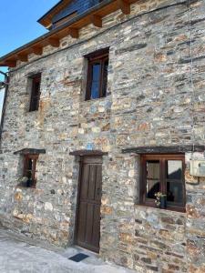 - un bâtiment en pierre avec une porte et trois fenêtres dans l'établissement Medulillas 1 Casa a 2000 m de Las Médulas, à Yeres