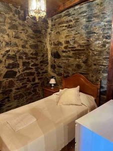 - une chambre avec un lit et un mur en pierre dans l'établissement Medulillas 1 Casa a 2000 m de Las Médulas, à Yeres
