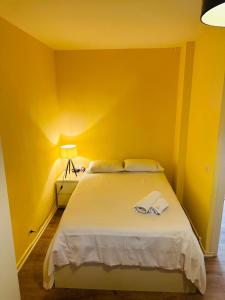 1 dormitorio amarillo con 1 cama con 2 toallas en Charmant studio très accueillant en Ginebra