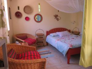 a bedroom with a bed and two wicker chairs at Aloepark Art Hotel in Naivasha