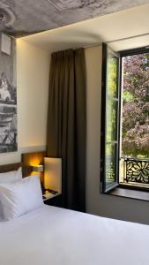 a bedroom with a white bed and a window at Hôtel du Château in Villers-lès-Nancy