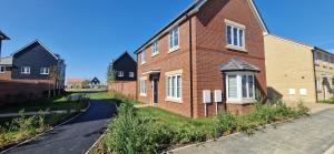 una casa di mattoni rossi con una strada accanto di Brand new Entire 4-Bed House in Peterborough a Peterborough
