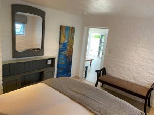 a bedroom with a bed and a mirror and a bench at Lemon-Lime Cottage Darling in Darling