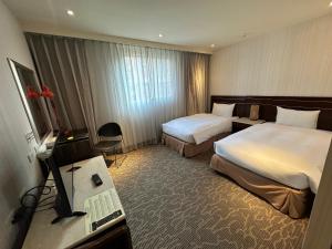 a hotel room with two beds and a television at Young Soarlan Hotel - Tainan in Tainan