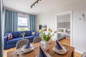 a living room with a blue couch and a table at Ambria Apartments Sun Towers in Świnoujście