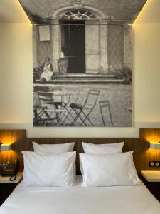 a bed with a black and white picture above it at Hôtel du Château in Villers-lès-Nancy