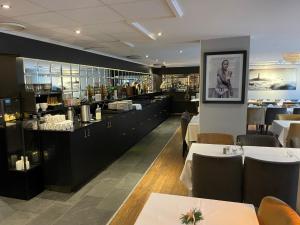 um restaurante com mesas e cadeiras e um bar em Tvedestrand Fjordhotell - Unike Hoteller em Tvedestrand