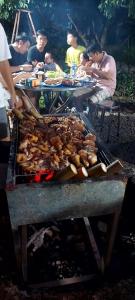 a group of people sitting around a grill at Thuy Tien Ecolodge in Cat Tien