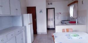 Cyangugu的住宿－Centre d'Accueil Casa dell'Annunciazione Rusizi- Kamembe- Cyangugu -Rwanda，白色的厨房配有桌子和冰箱