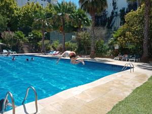 a woman jumping into a swimming pool at Rocha Gardens Apartment in Portimão