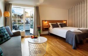 Tvedestrand Fjordhotell - Unike Hoteller في تيفيديستراند: غرفة نوم بسرير واريكة وطاولة