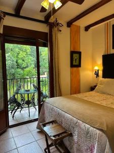 a bedroom with a bed and a balcony with a table at Hotel Rural Convento Santa Maria de la Sierra in Arroyo Frio