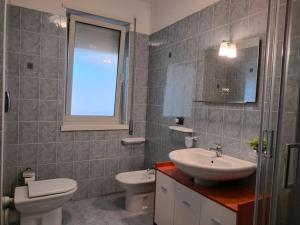 een badkamer met een wastafel, een toilet en een spiegel bij Casa quinto piano - intero appartamento con garage in Vicenza
