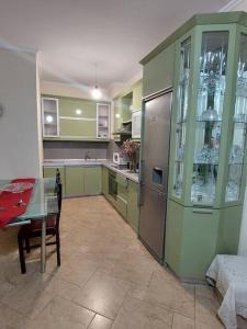 eine Küche mit grünen Schränken, einem Tisch, einem Tisch und einem Tisch sowie einem Tisch in der Unterkunft Buneci apartment in Tirana