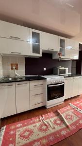 uma cozinha com armários brancos e um lavatório em Mountain View Cozy House em Baytyk