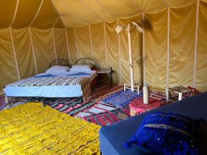 uma tenda com duas camas num quarto em Authentique berber Camp em M'hamid