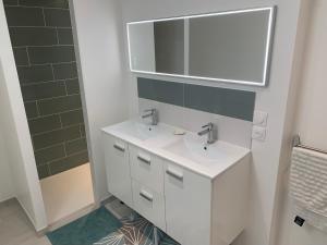 a bathroom with a white sink and a mirror at Maison rénovée au calme in Biéville-Beuville